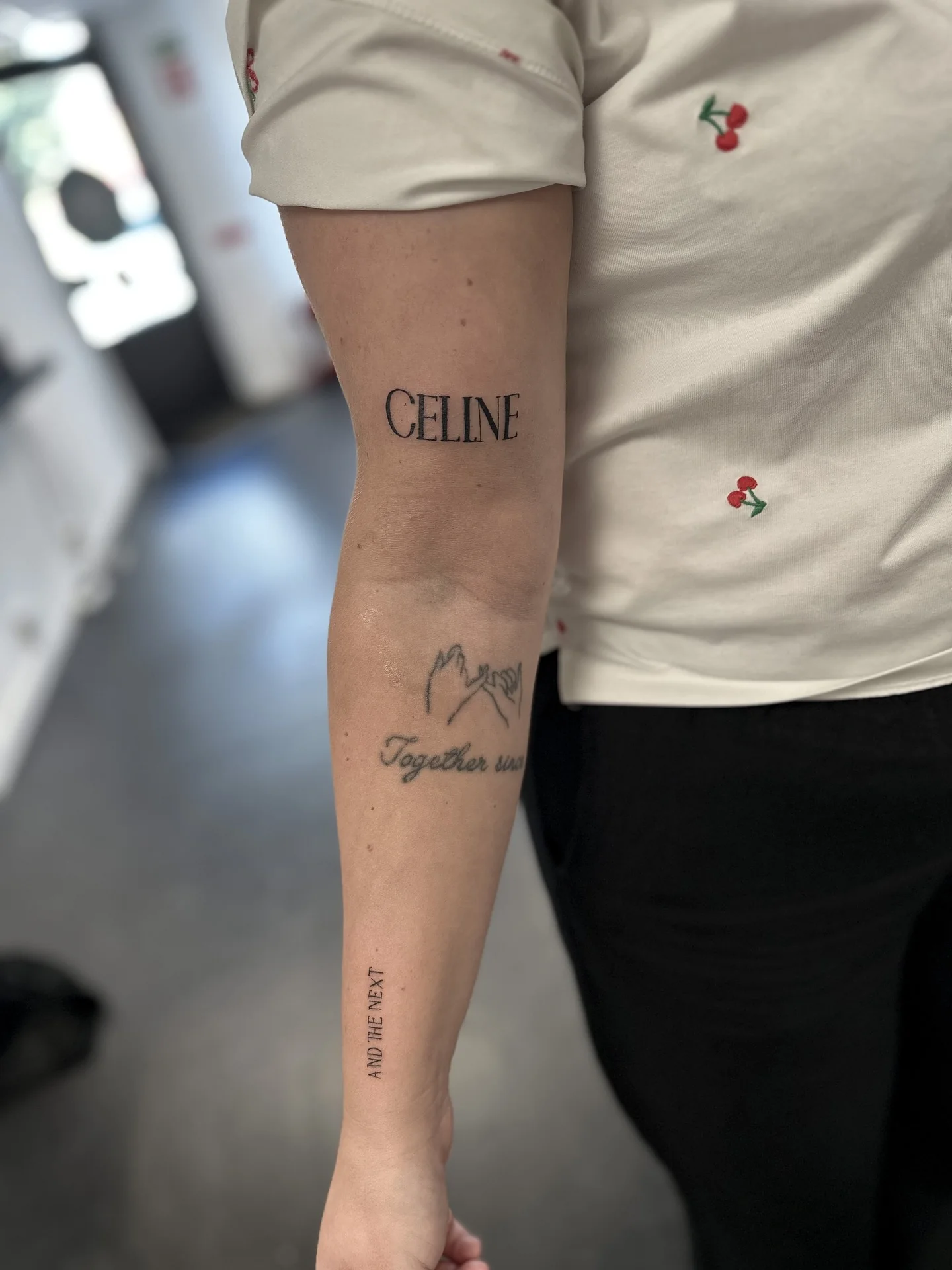 Fin lettering och små symboliska tatueringar på underarm